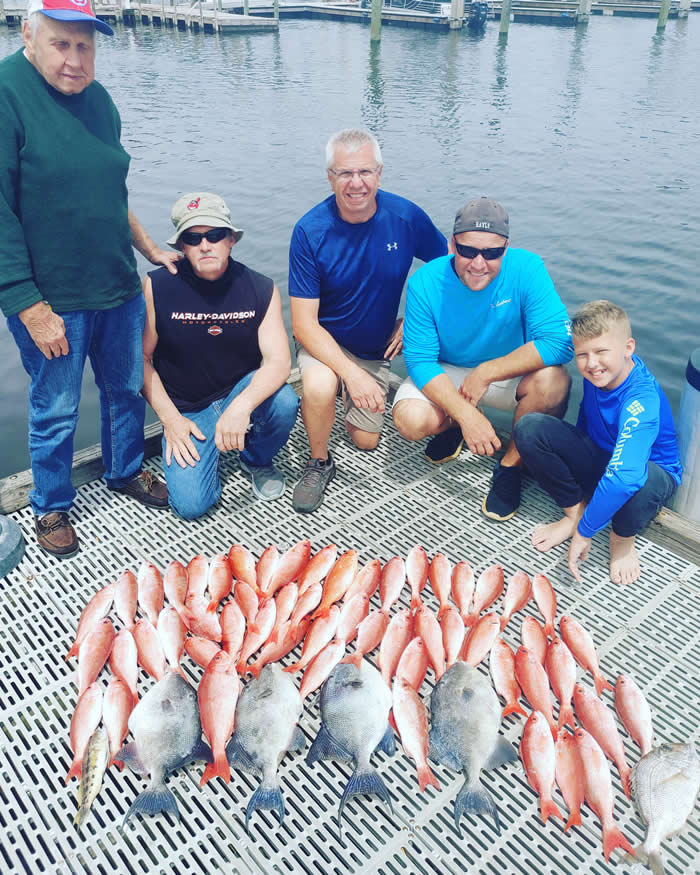 A group of anglers with their catch after a Pensacola fishing trip with Next Generation Fishing Charters